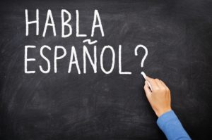Spanish language learning concept image. Teacher or student writing "habla espanol" on blackboard during spanish language course class.