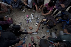 Nepalese villagers charge their cell phones in an open area in Kathmandu, Nepal, Monday, April 27, 2015. Shelter, fuel, food, medicine, power, news, workers — Nepal's earthquake-hit capital was short on everything Monday as its people searched for lost loved ones, sorted through rubble for their belongings and struggled to provide for their families' needs.. (AP Photo/Bernat Armangue)